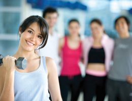 woman at the gym exercising with free weights in front of a group